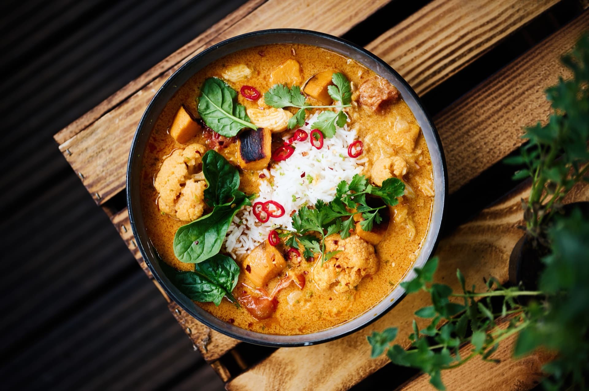 A bowl of fragrant curry with basmati rice, cauliflower, sweet potato, fresh coriander and red chilli