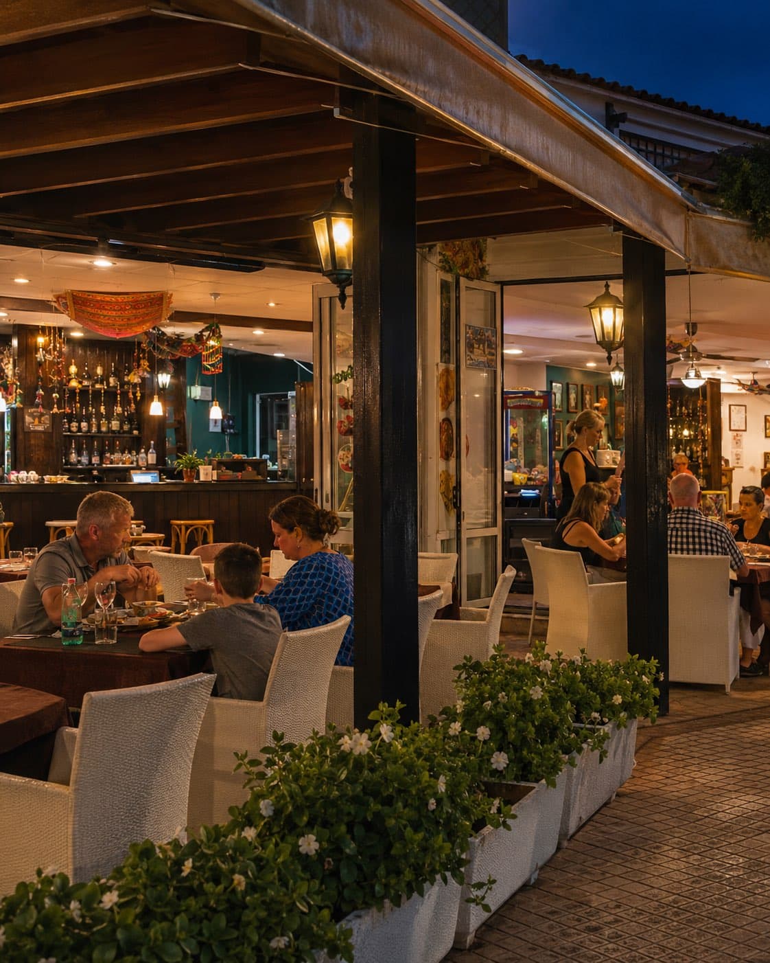 Guests dining on Taste of India's covered terrace at dusk, lit by warm lanterns
